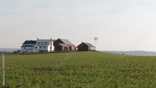 Amish Farm with Windmill on Top of a Green Field on a Hill