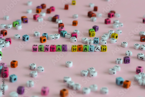 Mental health words are written in different color blocks placed on a pink surface