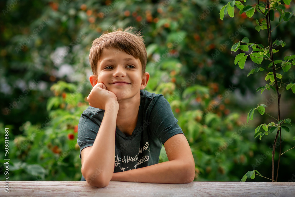 a boy is sitting in a green garden and looking away a boy is sitting in a green garden and looking away