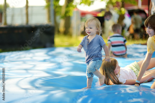 Obraz na plátně Cute little toddler boy bouncing on huge water filled jumping pillow