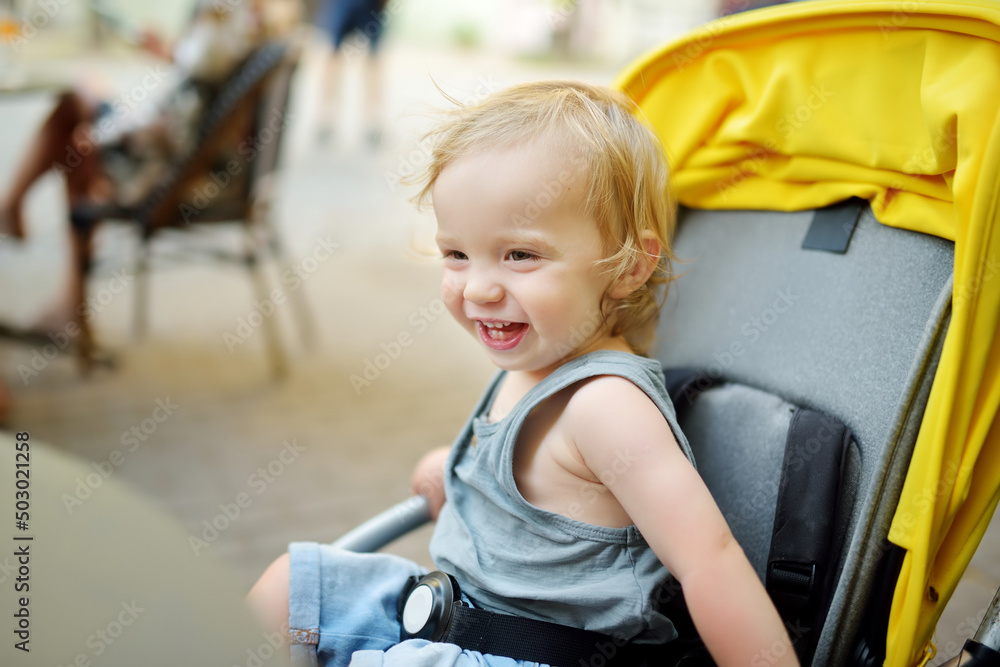 Sweet toddler boy sitting in a stroller outdoors. Little child in pram. Infant kid in pushchair. Summer walks with kids. Sweet toddler boy sitting in a stroller outdoors. Little child in pram. Infant kid in pushchair. Summer walks with kids.