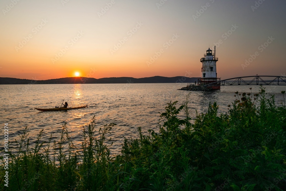 Silhouette of a kayaker at sunset with a lighthouse
