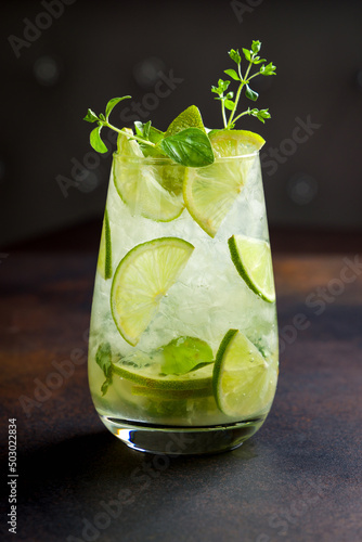classic Mojito with lime and ice on dark stone brown talbe side view photo