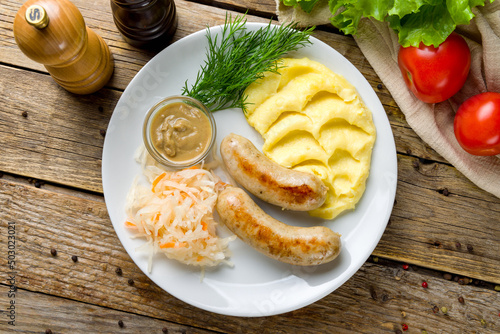 bavarian sausages with mashed potatoes and mustard on white plate on wooden table top view