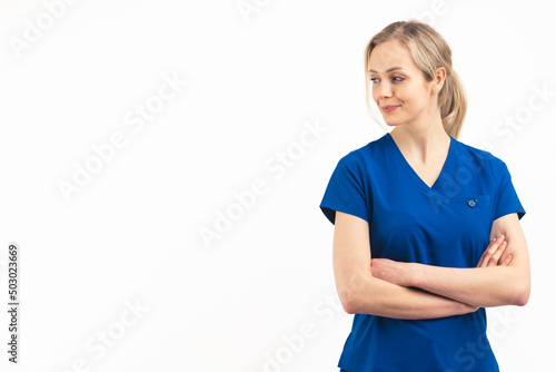 European blonde female helath care worker in a navy blue medical uniform standing with her arms crossed on her chest looking away. Studio shot on white background, copy space. High quality photo photo