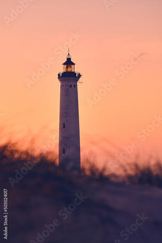 Lighthouse in warm morning glow above the dunes. High quality photo
