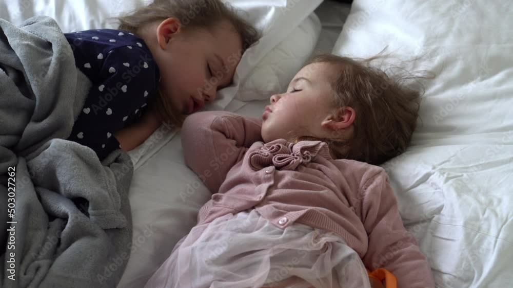 Authentic Two Cute Little Girls Sister Sleeping Sweetly Together In Comfortable White Bed. Beautiful Tired Child Have Rest Time Gently Soothing. Kids Resting. Care, Childhood, Parenthood, Life concept Authentic Two Cute Little Girls Sister Sleeping Sweetly Together In Comfortable White Bed. Beautiful Tired Child Have Rest Time Gently Soothing. Kids Resting. Care, Childhood, Parenthood, Life concept