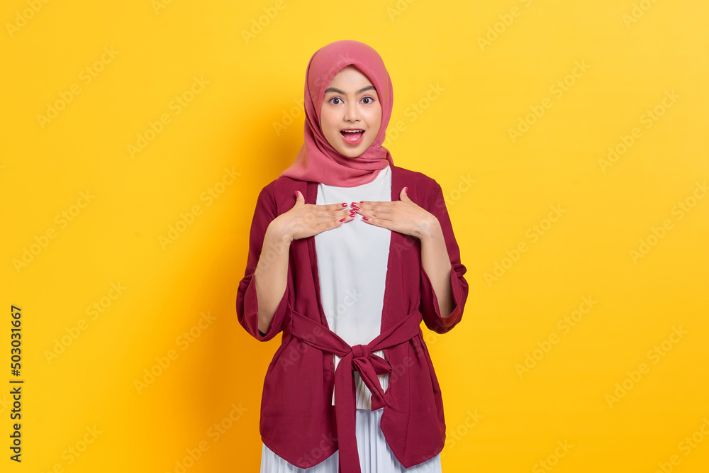 Amazed beautiful Asian woman in casual shirt looking at camera with opened mouth isolated over yellow background