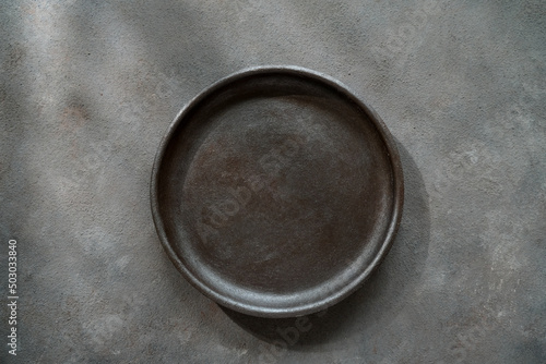 Empty black ceramic plate on concrete table. Round plate mockup.