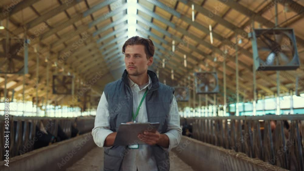 Livestock owner checking animal feedlots making notes on clipboard at cowshed. Livestock owner checking animal feedlots making notes on clipboard at cowshed.