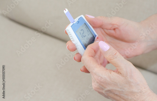 Woman taking blood sample from her finger for glucometry. Diabetes. Glucose control. Glucometer. Blood glucose level. Device with lancet for glucometry.