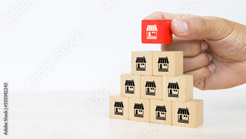 Franchise, Close-up hand choose cube wooden toy block stack with franchises business store icon for franchising business marketing plan to growth and branch expansion and banking loan.