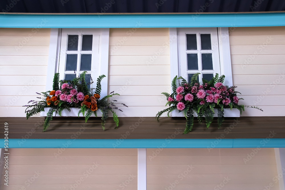 Front of a wooden house plank wall with white windows  and flowers decorative on background