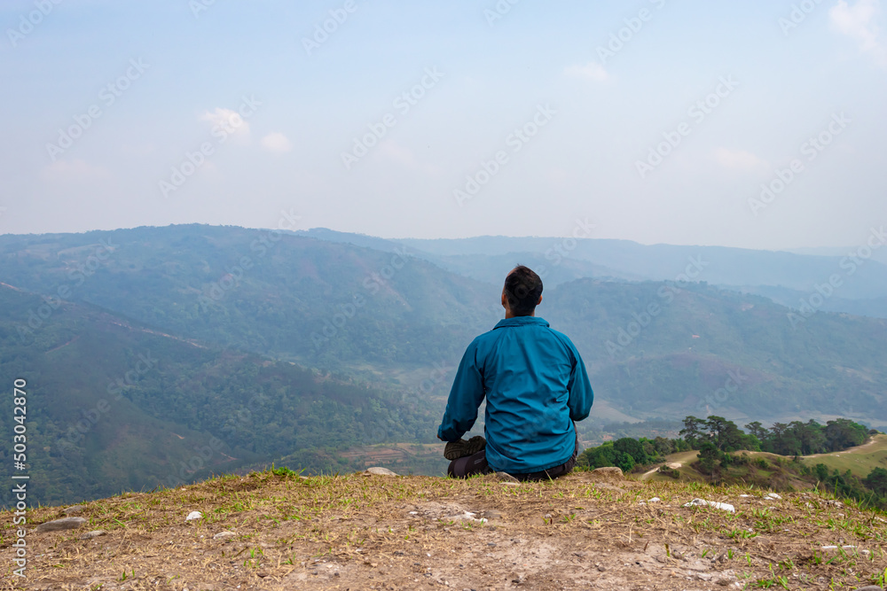 man meditating at hill top with misty mountain rage background from flat angle