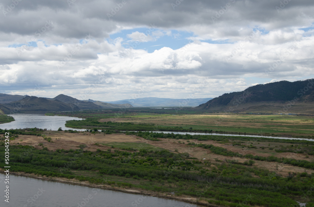 The valley of the river under an overcast cloudy sky. View of the river from a height.