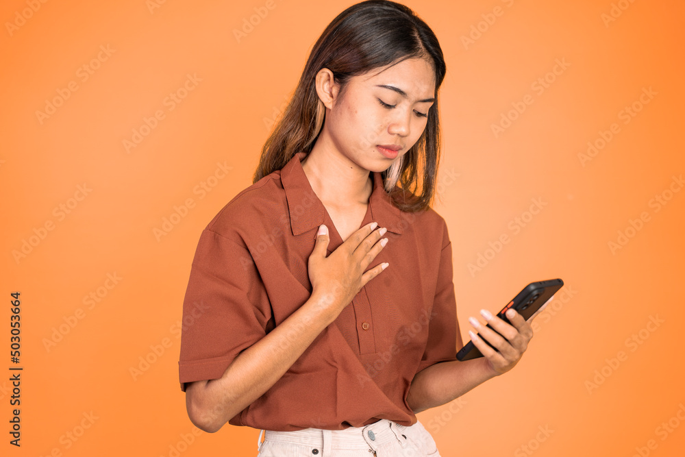 Sad asian young woman while using mobile phone on isolated background Sad asian young woman while using mobile phone on isolated background