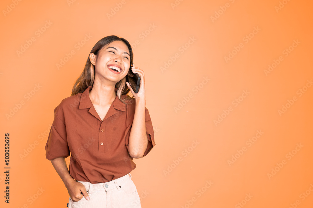 Young asian woman making a call using a cell phone on isolated background Young asian woman making a call using a cell phone on isolated background