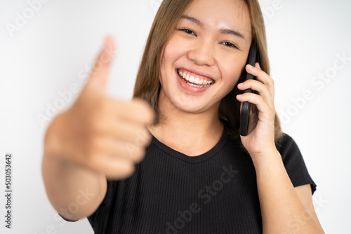 young woman using mobile phone with thumbs up on isolated background