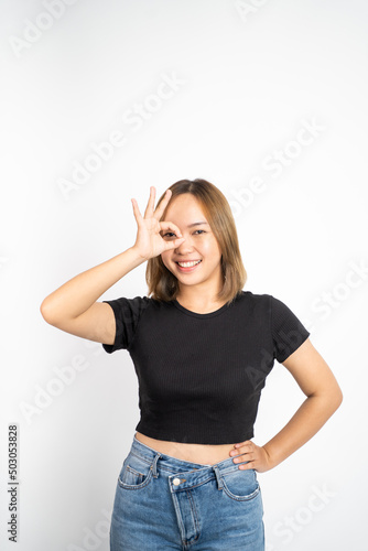 Young woman showing oke gesture with hands near eye looks imitating binoculars on isolated background © Odua Images
