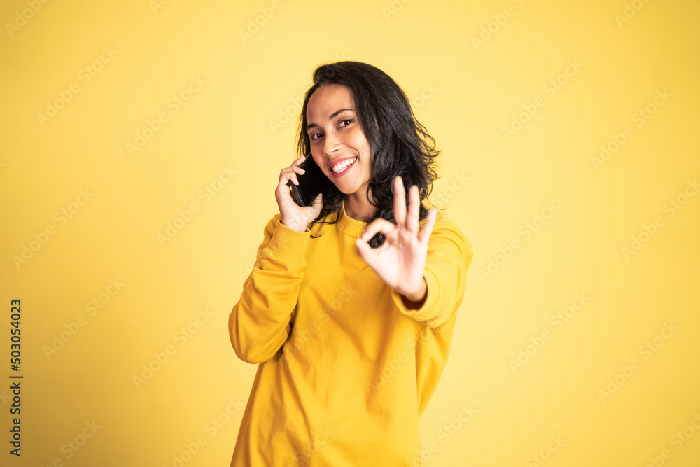 Obraz premium young woman using mobile phone with thumbs up on isolated background