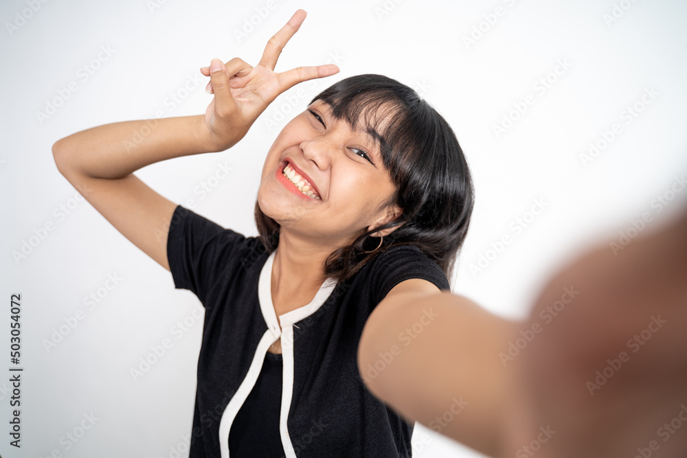 attractive woman take a selfie using mobile phone camera with v sign finger gesture on isolated background attractive woman take a selfie using mobile phone camera with v sign finger gesture on isolated background