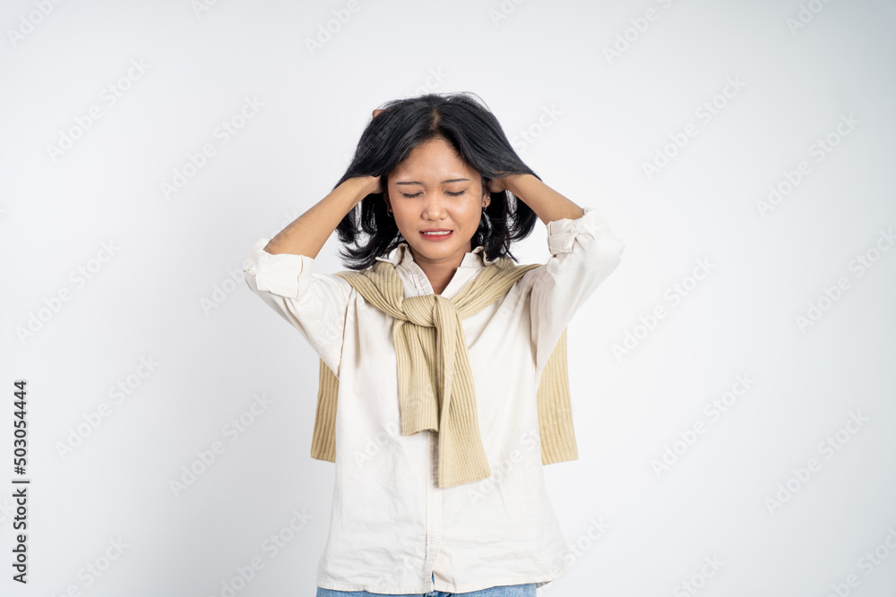 frustrated Asian young woman holding head with headache on isolated orange background frustrated Asian young woman holding head with headache on isolated orange background