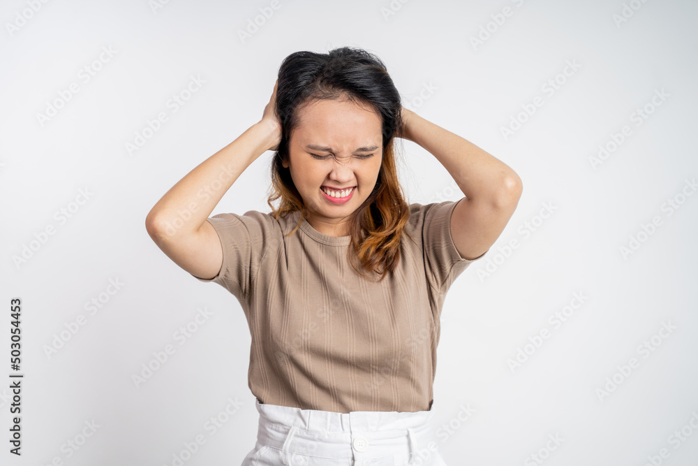 frustrated Asian young woman holding head with headache on isolated orange background frustrated Asian young woman holding head with headache on isolated orange background