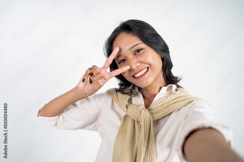 attractive woman take a selfie using mobile phone camera with v sign finger gesture on isolated background attractive woman take a selfie using mobile phone camera with v sign finger gesture on isolated background