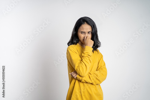 Young woman covering nose with finger when bad smell on isolated background © Odua Images