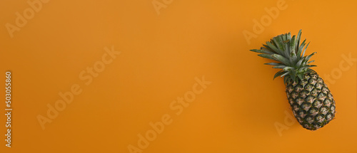 Top view with a delicious and juicy pineapple on the empty yellow background.