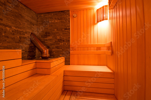 Seat in sauna room. Empty wooden steam room with stone heater.Sauna room for good health. Sauna room with traditional sauna accessories.Healthy and spa life style.