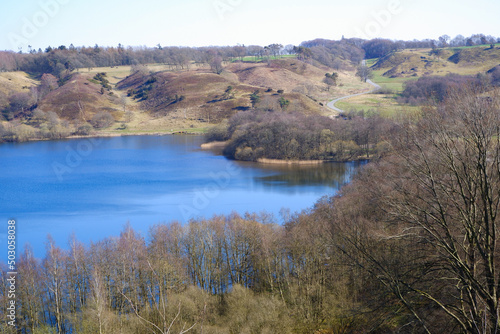 Landscape. Blue lake with wooded hilly shores in early spring.