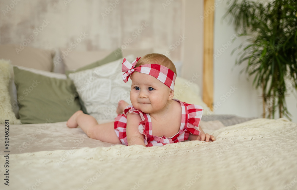 caucasian baby girl in a plaid bodysuit crawls on the bed in the room caucasian baby girl in a plaid bodysuit crawls on the bed in the room