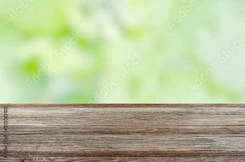 An empty brown wooden table. Blurry summer or spring background.