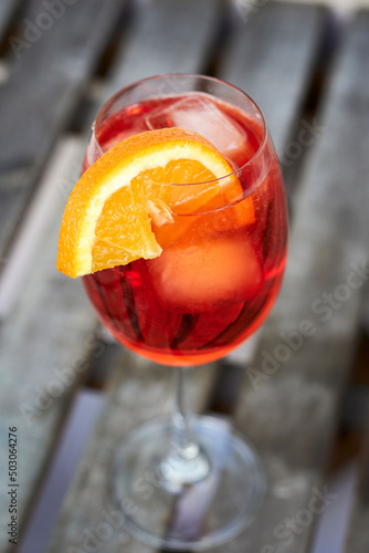 Closeup shot of a fresh Spritz Veneziano Cocktail with an orange slide on a woodenn board background photo