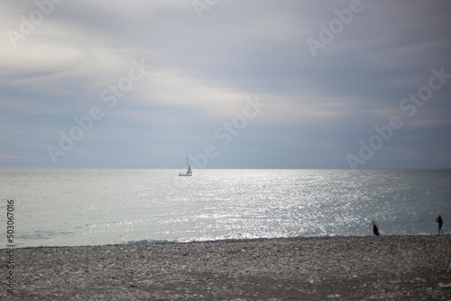 Sea shore. Sailing boat far into the sea. Girls on the shore. Seascape. Calm wave. © Олег Копьёв
