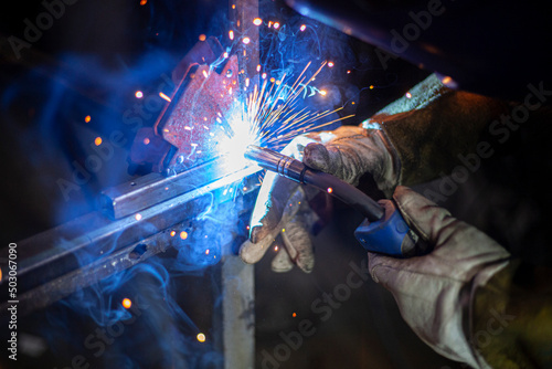 Metal welding. Fire from operation of welding machine. Manufacture of steel seam. Processing of steel profile. Sparks from welding.