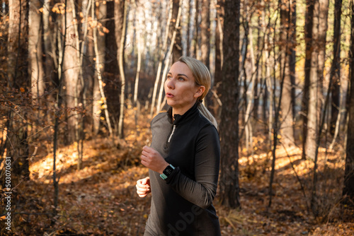 A young attractive blonde woman is jogging in the park during sunset. Outdoor exercises. Healthy lifestyle concept
