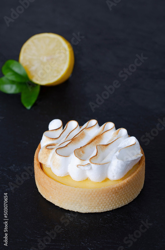 Tart lemon cheesecake on a black background with fresh lemon 