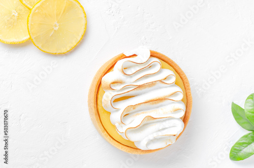 Mini lemons tart with cream on white background. Lemons slices and green leaves 