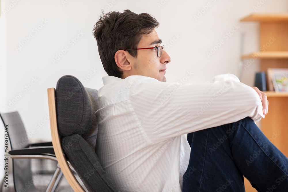 Fototapeta premium Junger Mann arbeitet in einem Büro und macht Gedankenpause