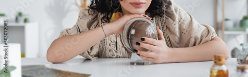 Cropped view of soothsayer touching glass orb at home, banner. photo