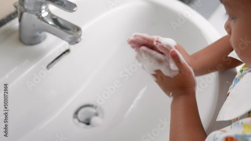Small girl washing her hands to prevent virus, bacteria and germs at sink.