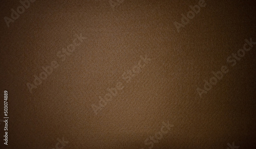 Photo of the texture of a brown background made of soft felt fabric.Rag brown background with black vignette. photo