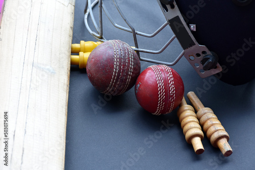 Old training cricket sport equipments on dark floor, leather ball, wickets, helmet and wooden bat, soft and selective focus, traditional cricket sport lovers around the world concept.