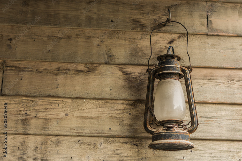rusty storm lamp hanging on a wooden wall