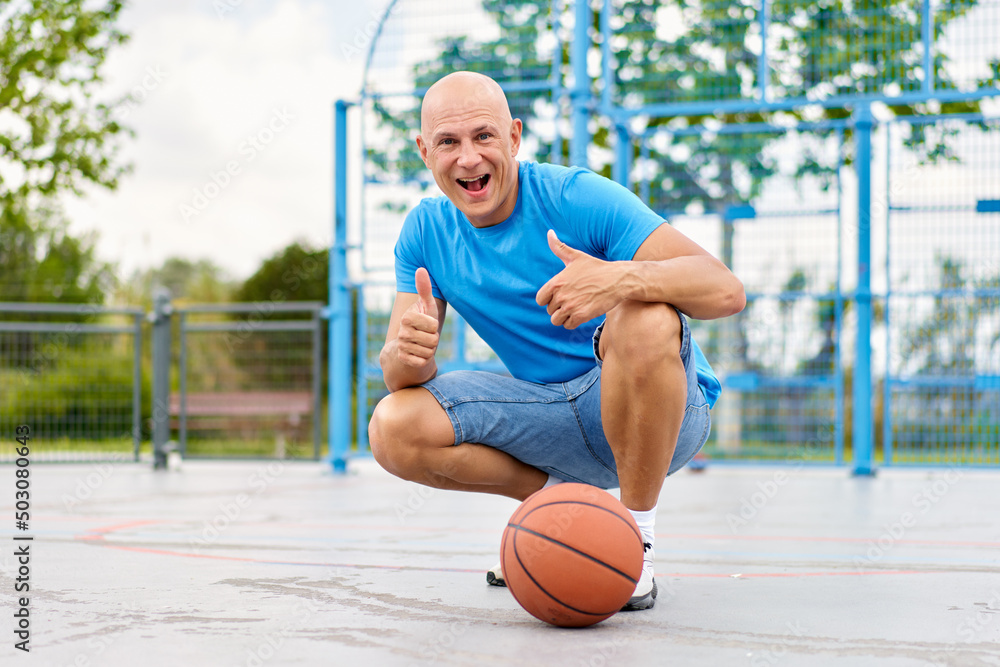 Handsome man carrying a basketball ball and looking at camera