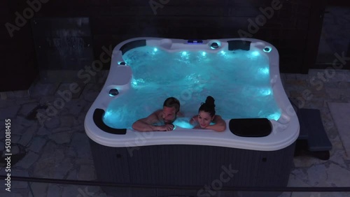 Romantic young couple relaxing in the hot tub with lights photo