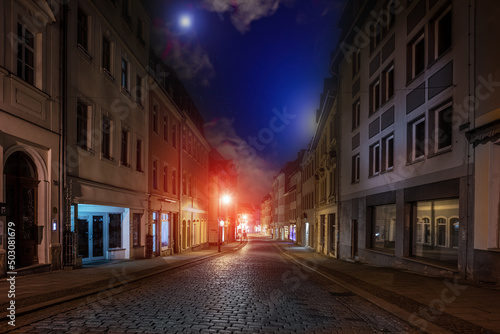 Street of an old European city with paving stones at night with street lamps and blue sky