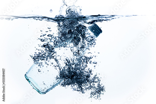 a bottle of drinking water falls into the water on a white background